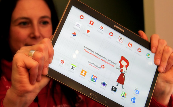 An image showing a woman holding up a tablet. On the screen is information about medical solutions.