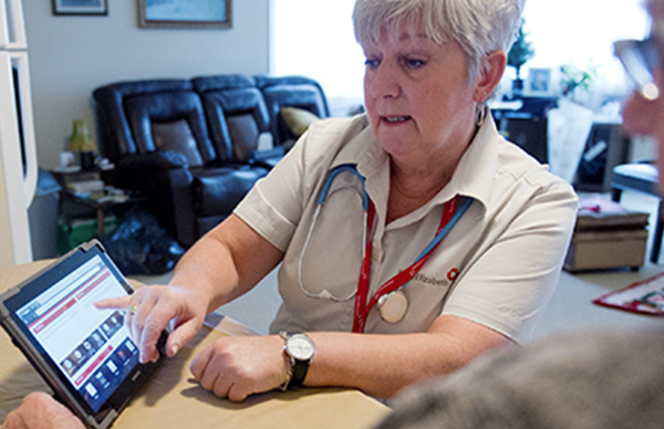 An image showing a nurse explaining something to a patient, using materials shown on a tablet screen. If you click on the image, you can navigate to the Saint Elizabeth detail page.