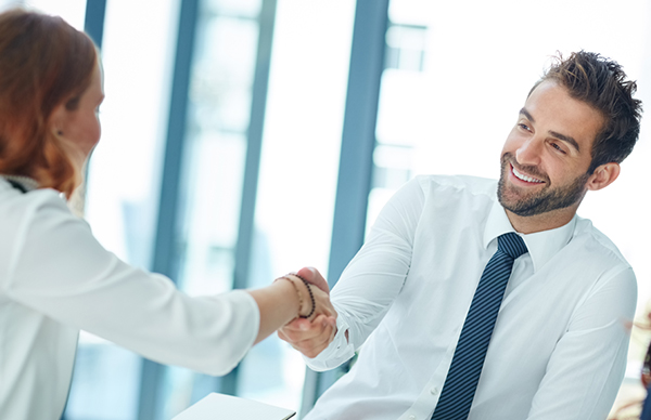 An image showing two smiling office workers shaking hands